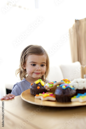 Little girl looking at confectionery at home