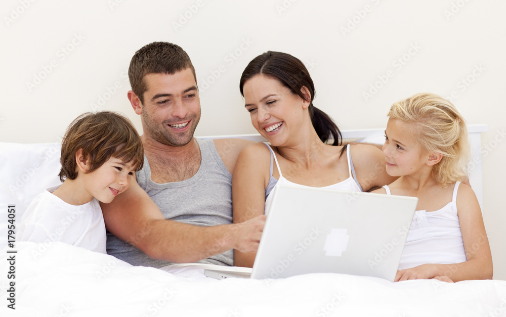 Parents and children using a laptop in bed Parents and children using a laptop in bed