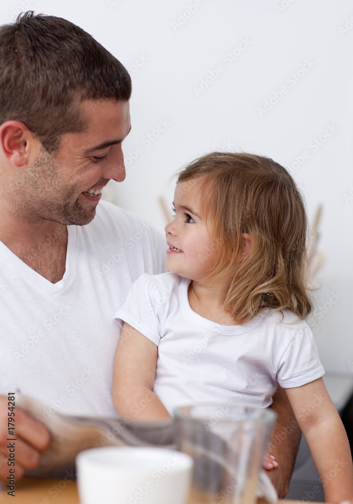 Father reading a newspaper smiling to his daughter Father reading a newspaper smiling to his daughter