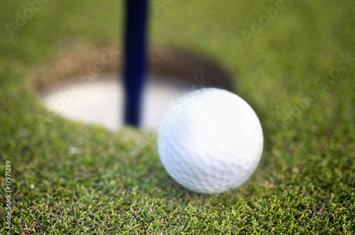 Golf ball rolling into hole on green