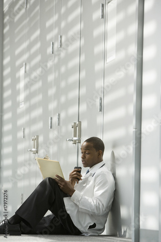 African doctor sitting on floor dictating medical record into recorder
