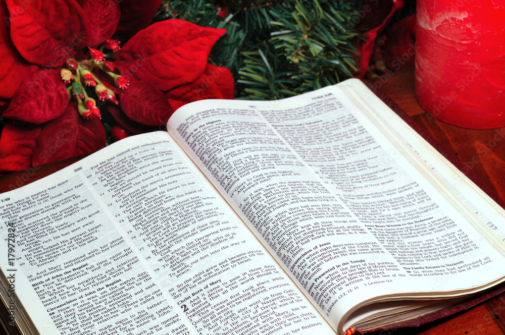 Bible open to the nativity story with poinsettia and candle Stock Photo ...