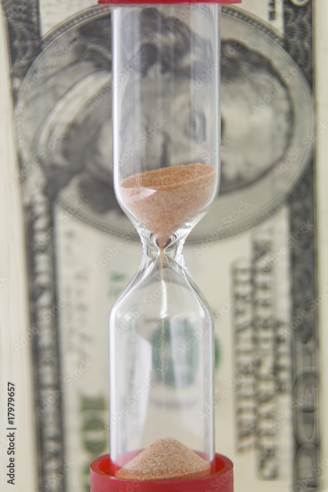 Closeup view of sand flowing through an hourglass on the backgro Closeup view of sand flowing through an hourglass on the backgro