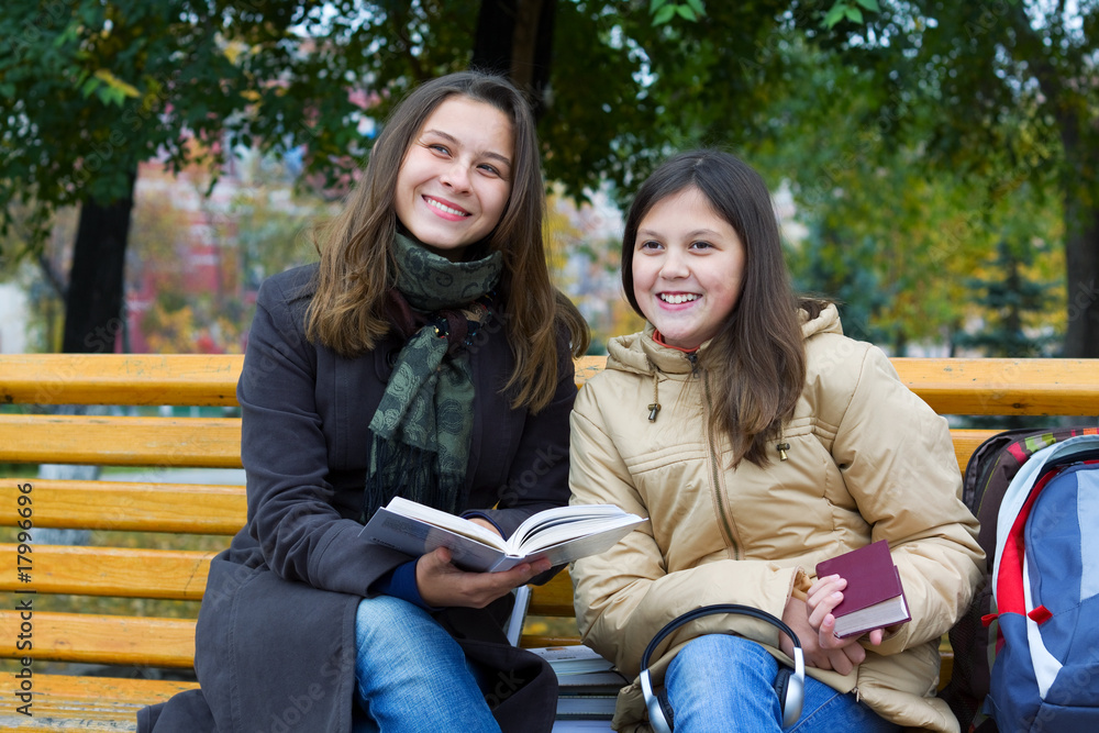 Two young girls reading in the park. Two young girls reading in the park.
