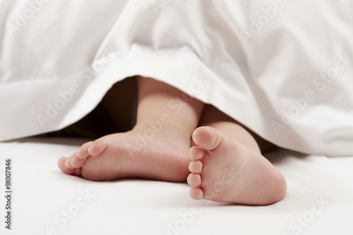 Baby feet on white bed