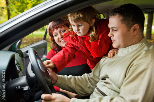 Married couple and little girl sit in car in park