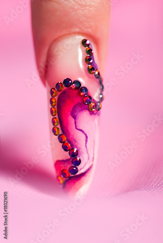 Human finger with long fingernail over pink