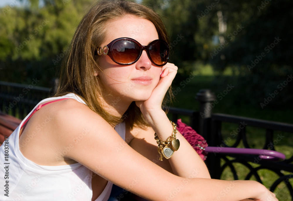 The young girl in sun glasses in park