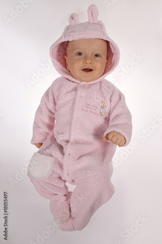 baby boy in pink rabit get-up on gray background