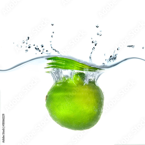 Fresh lime dropped into water with bubbles isolated on white