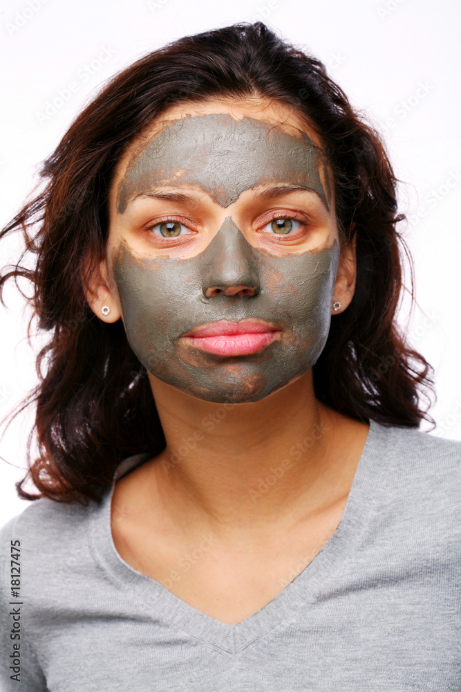 A funny girl with mud mask on a white background A funny girl with mud mask on a white background