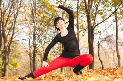 Pretty woman doing yoga exercises in the autumn park