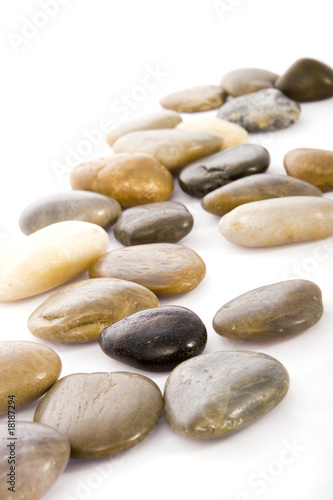 Obraz na płótnie An array of smooth, multicolored stones arranged on a white background, showcasing natural beauty and variety. Ideal for themes of tranquility, nature, or decoration. w salonie