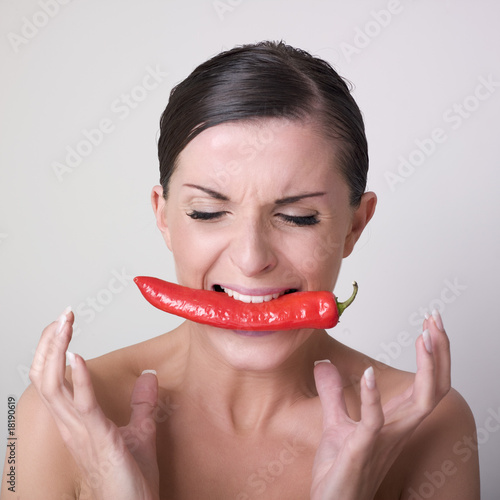 фотографія jeune femme nue mangeant un piment rouge