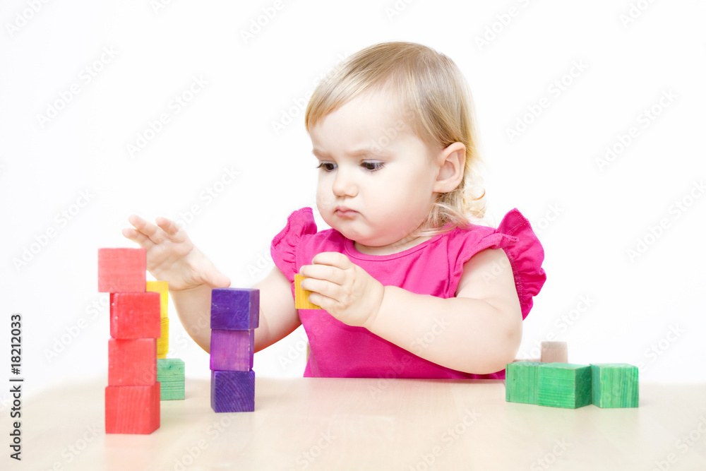 Serious little girl making towers from bricks Serious little girl making towers from bricks