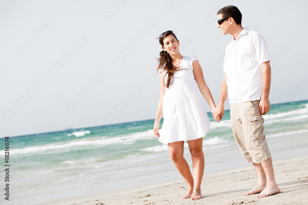 Young couple holding hands and walking on the beach Young couple holding hands and walking on the beach