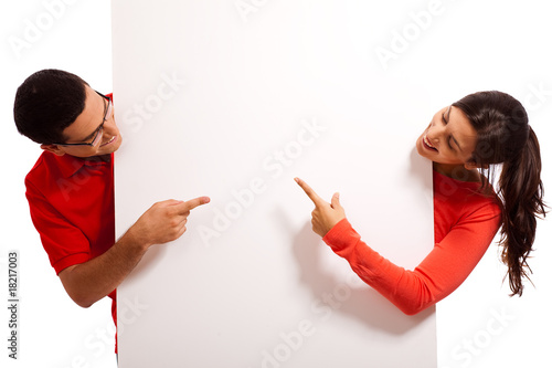 Playful young couple pointing the blank white baord photo