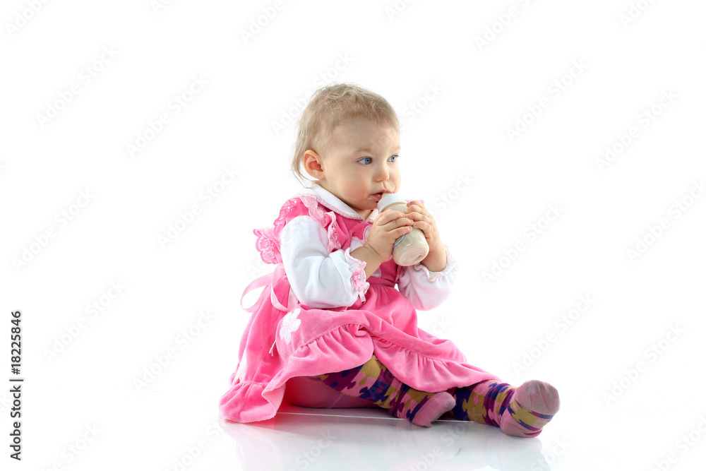 Pretty baby girl is drinking milk in a bottle isolated