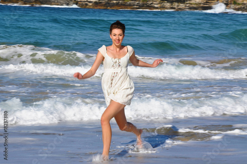 Beautiful young girl runs in the water on Bondi Beach photo