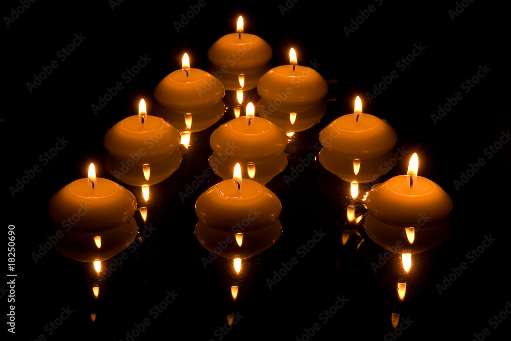 Mirrored burning candles floating on water