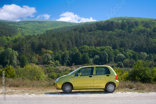 Small olive green car against the background of mountain landsca