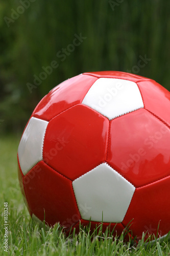 Red soccer ball on grass and green background