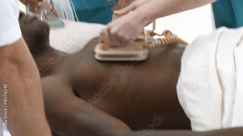 Doctors resuscitating a young man with a defibrillator