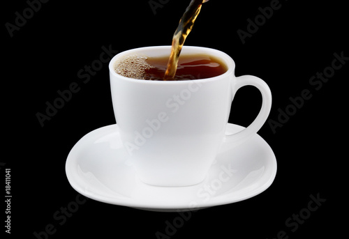 Pouring fresh tea to white cup isolated on black