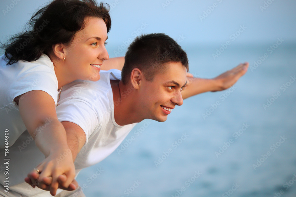 Smiling man and young woman placed hands in sides against sea Smiling man and young woman placed hands in sides against sea