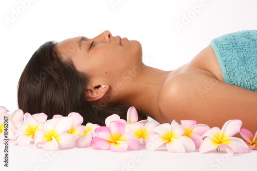 Frangipanis surround young woman with eyes closed in health spa