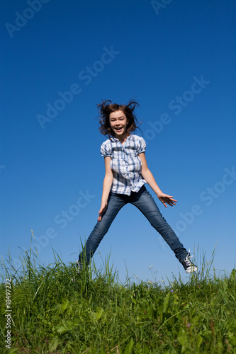 Girl running, jumping against blue sky