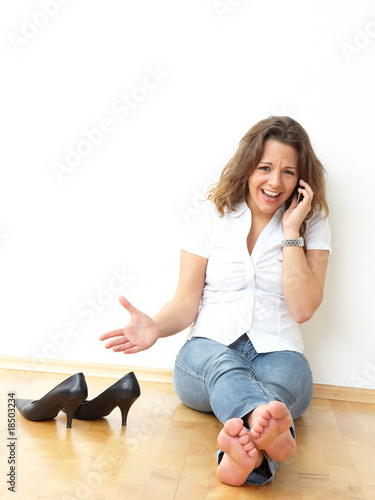 Beautiful girl sitting on the floor and making a phone call