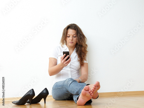 Young woman sitting on the floor writing a short message