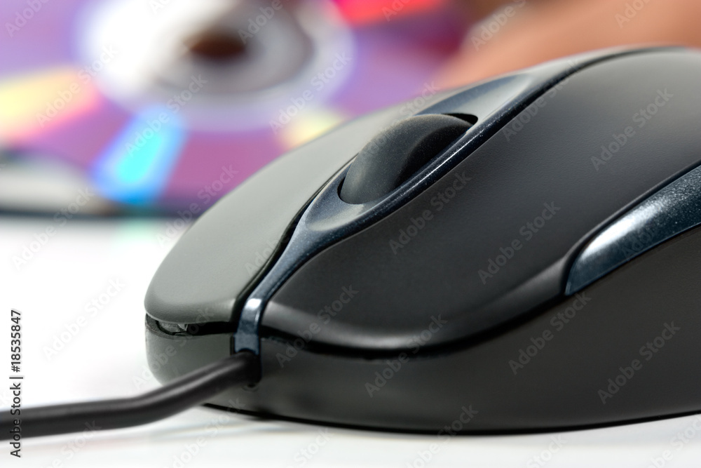 Black computer mouse and optical data disc in background Black computer mouse and optical data disc in background
