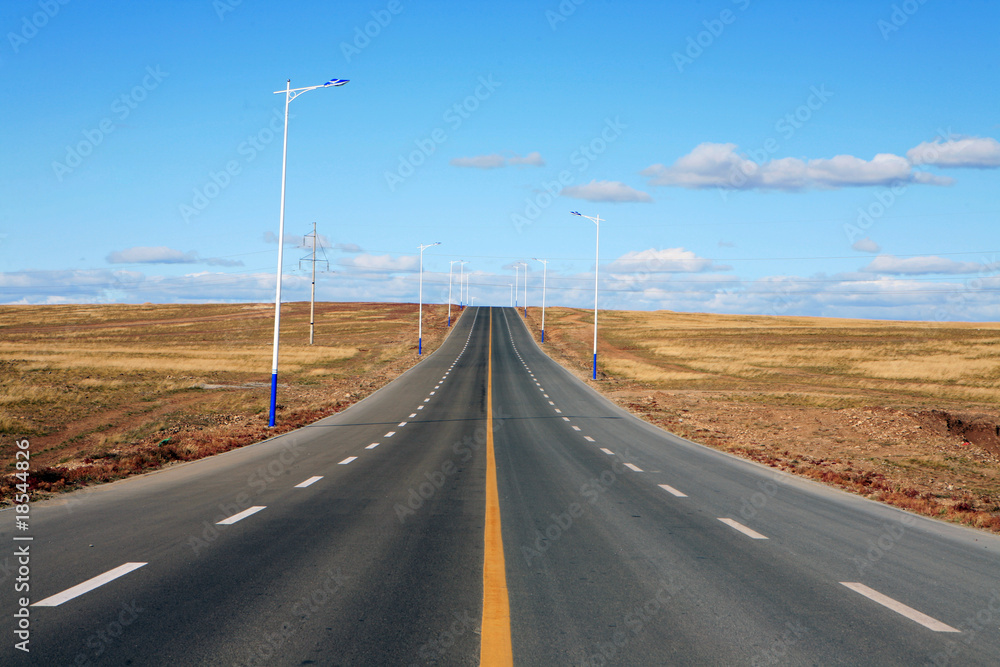 empty road in meadow with blue sky