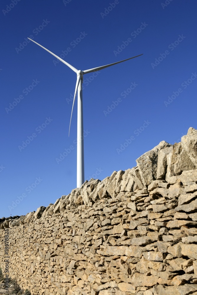 Fototapeta premium Electric windmills with a masonry rural wall