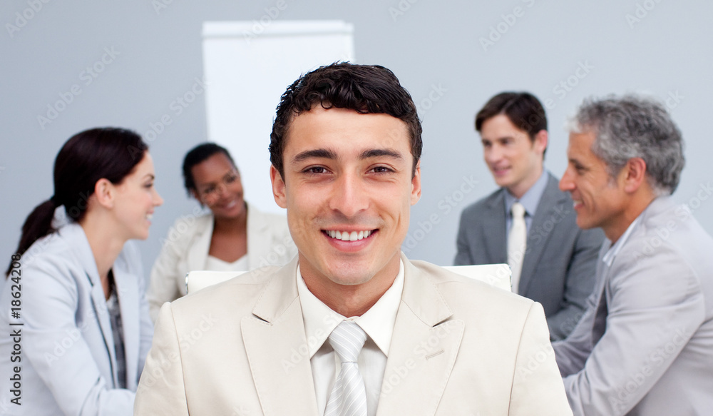 Smiling businessman sitting in front of his team in a meeting Smiling businessman sitting in front of his team in a meeting