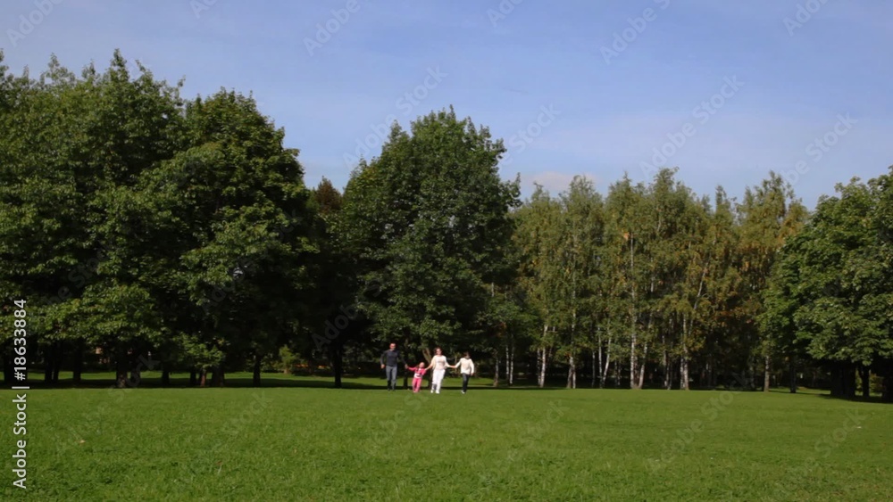 Family with boy and girl keeping for hands runs back on park Family with boy and girl keeping for hands runs back on park