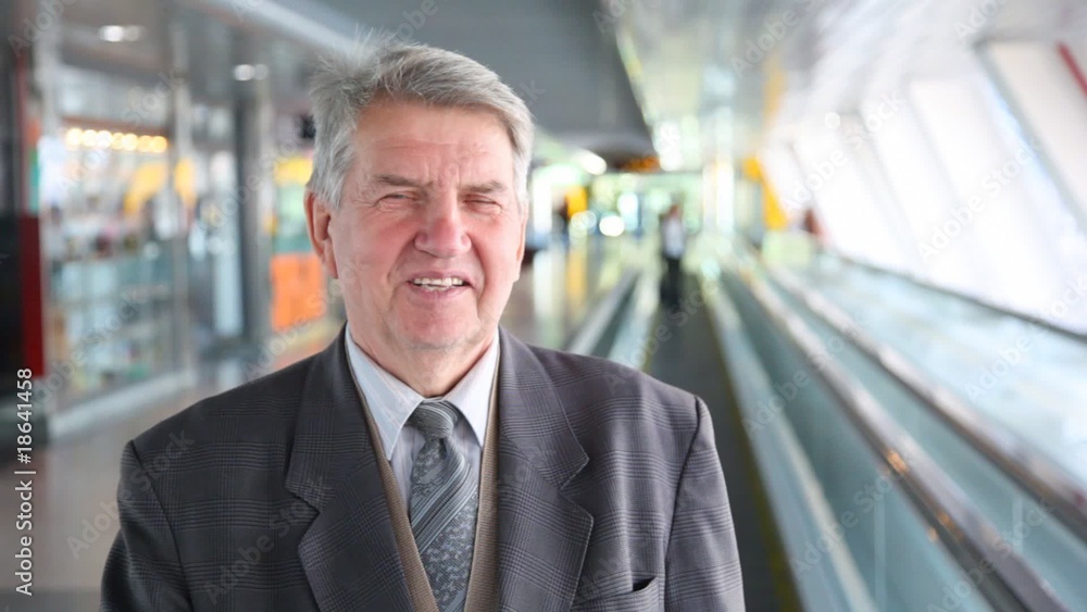 senior man in suit moving down on escalator senior man in suit moving down on escalator