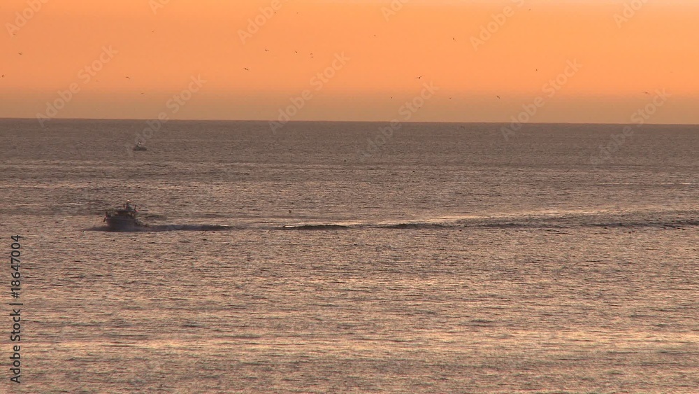 Trawler fishing boat coming to port at sunset Trawler fishing boat coming to port at sunset