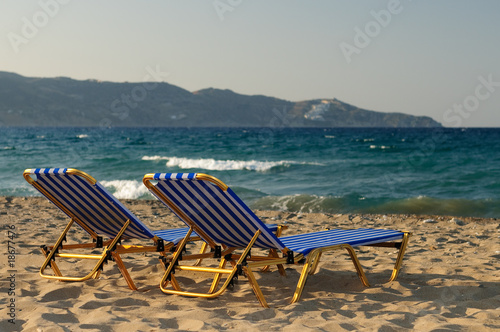 Two beachchairs in blue and white stripes on a beach © great_photos