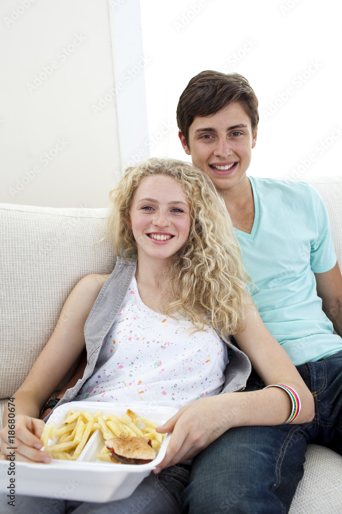 Teen couple eating burgers and fries