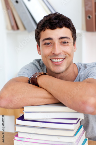 Smiling teeenager studying lots of books photo