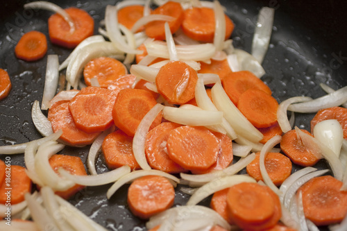 Karotten und Zwiebeln werden in der Pfanne angebraten photo