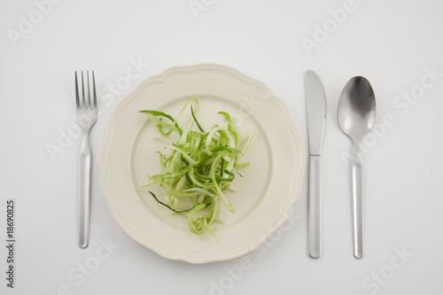 verdura su piatto con posate su sfondo bianco