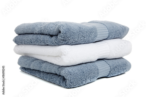 Gray blue and white towels with a bar of soap on white