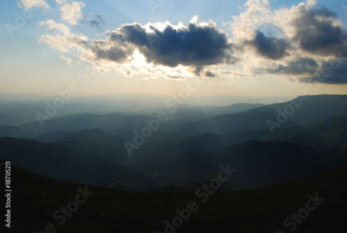 sunbeams passing trough clouds over hills