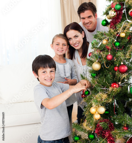 Smiling family decorating a Christmas tree