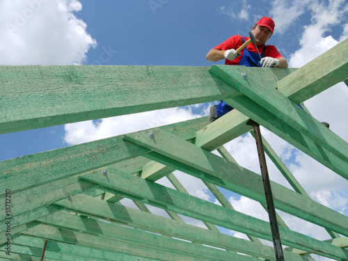 Quadro su tela Carpenter driving a nail into house rafter framing beam