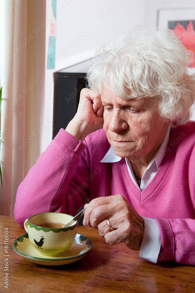 Depressed elderly woman sitting at the table Depressed elderly woman sitting at the table